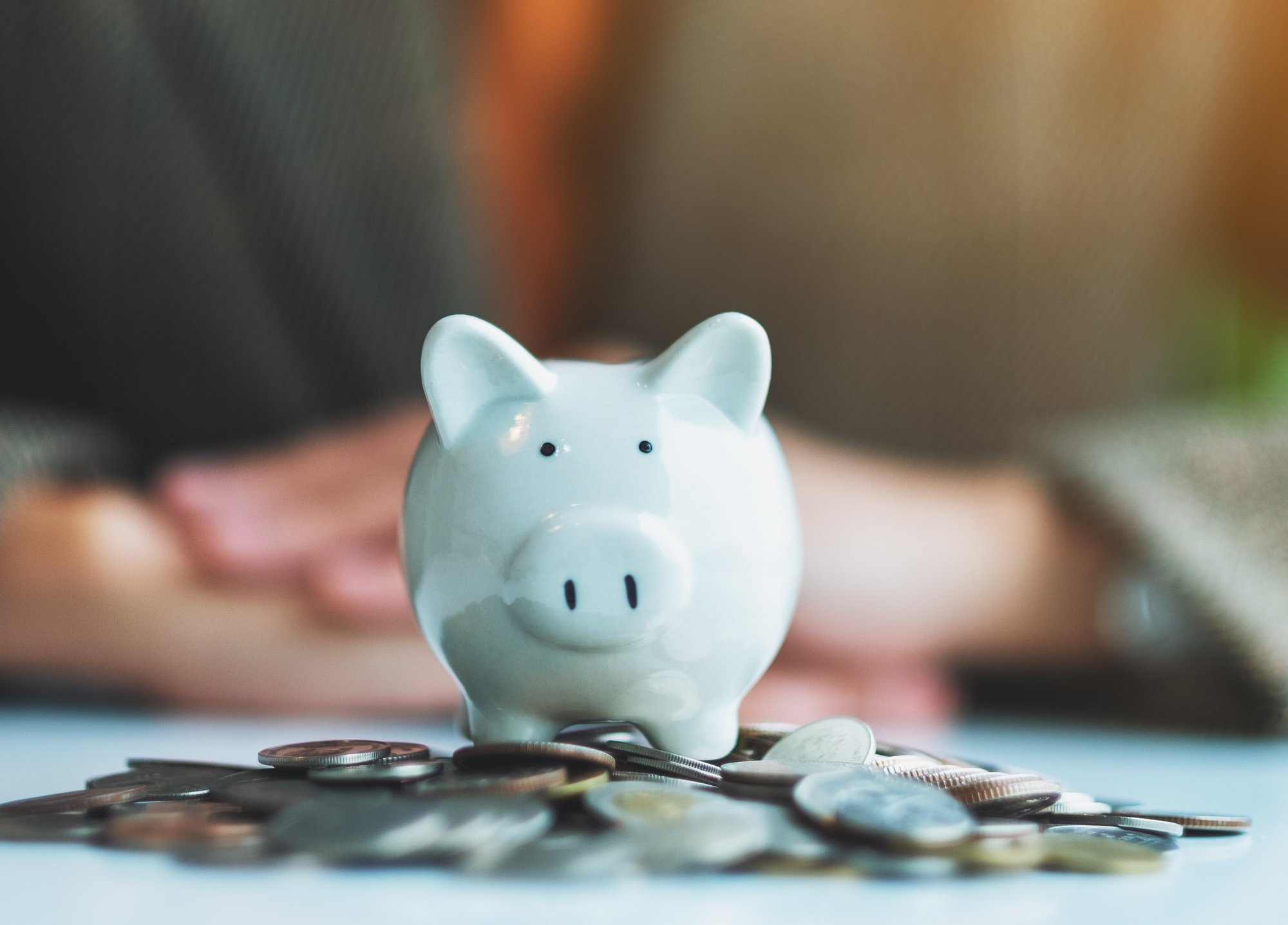 piggy-bank-on-coins-with-adult-in-background-2026-09-22-22-10-08-utc